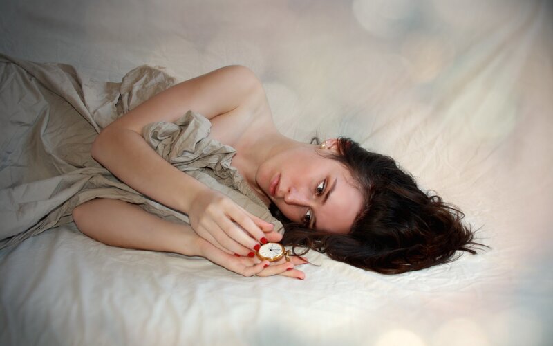 woman with pocket watch in bed