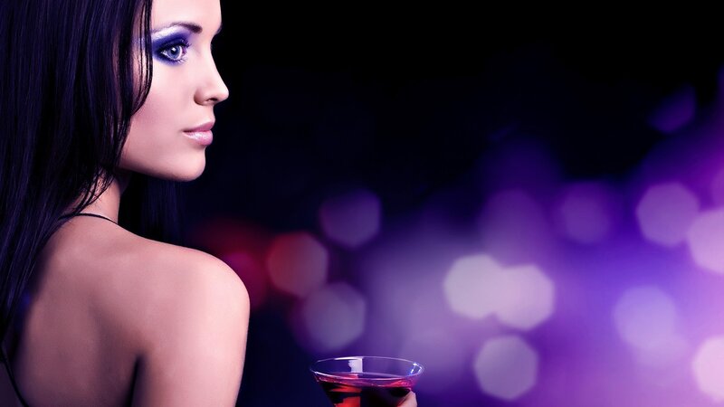 woman with purple makeup holding drink