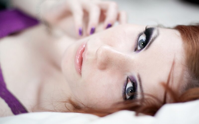 woman with purple makeup lying down