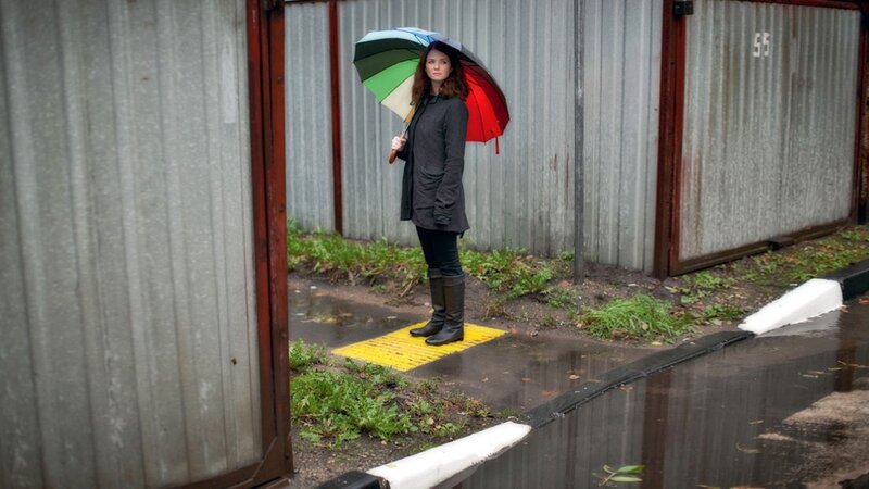 Woman with rainbow umbrella in rain