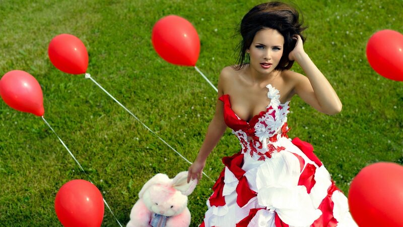 Woman with red balloons in field