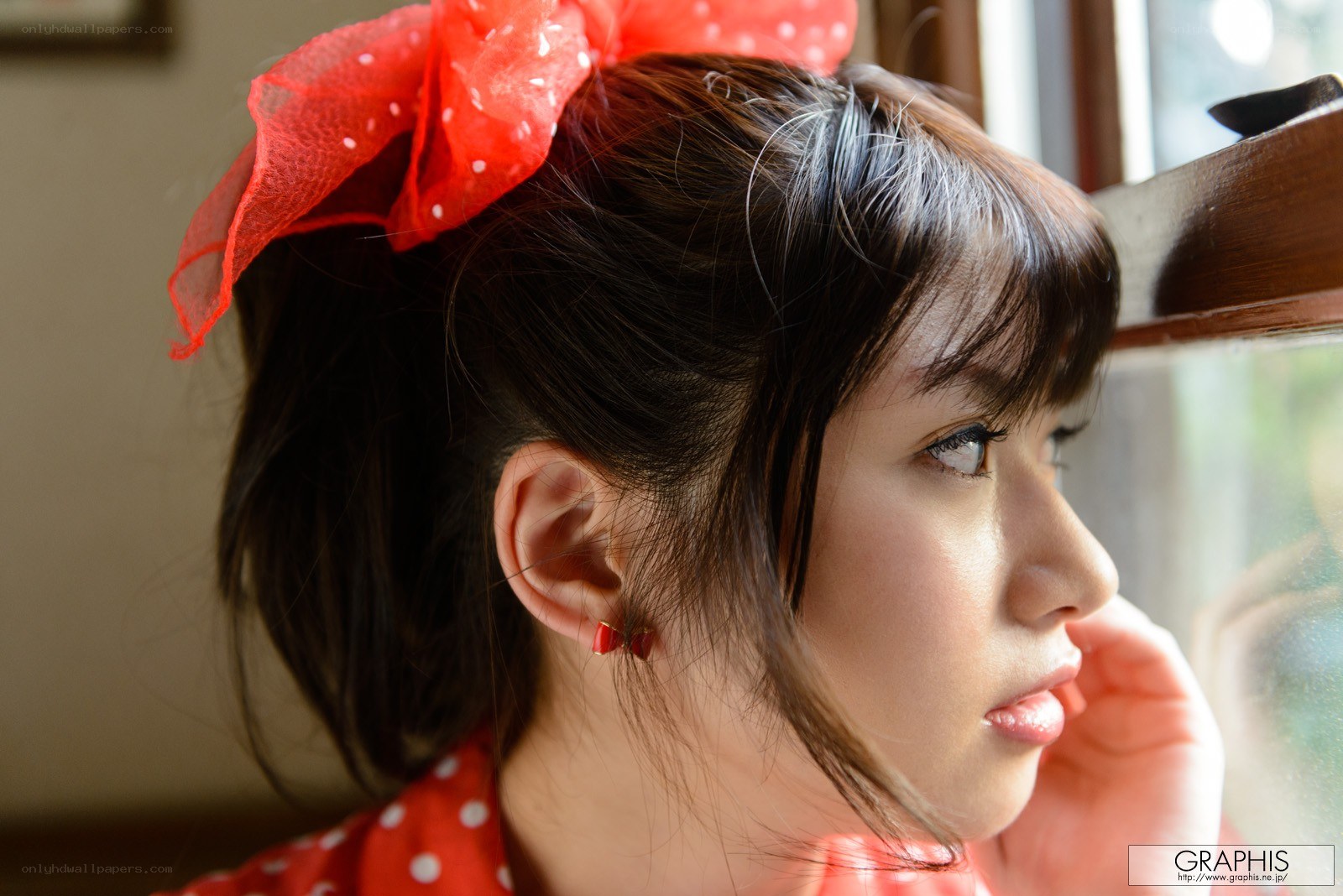 woman with red bow looking out window