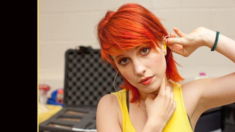 woman with red hair adjusting earpiece