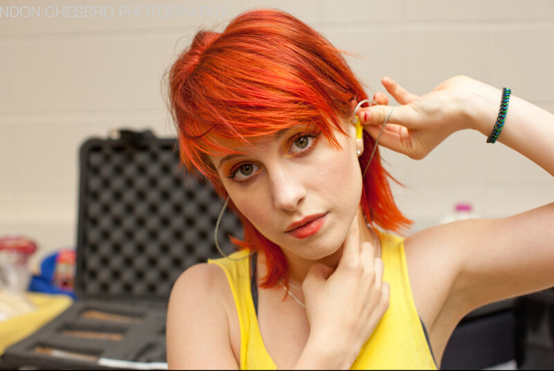 woman with red hair adjusting earpiece