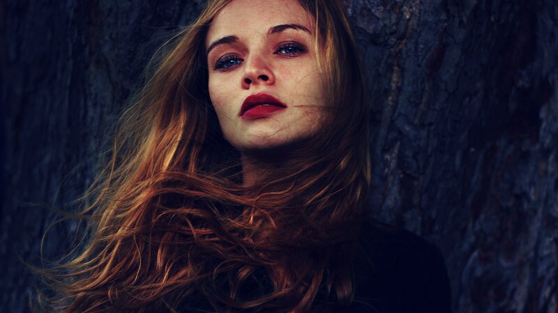 woman with red hair against tree
