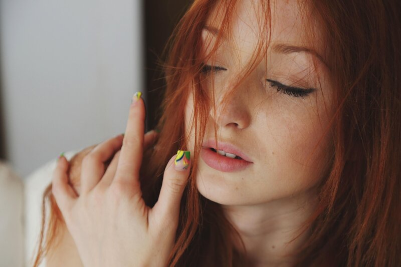 woman with red hair and colorful nails
