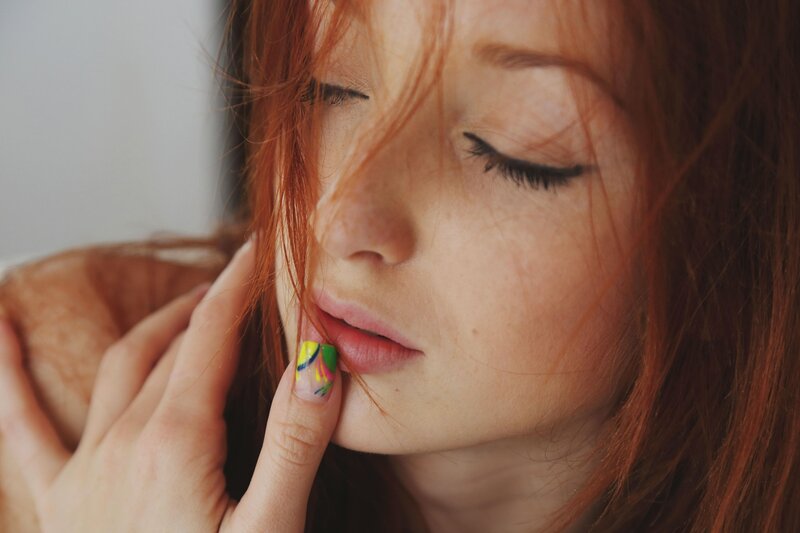 woman with red hair and colorful nails