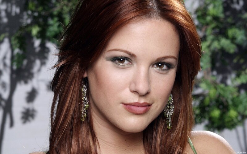 woman with red hair and green earrings