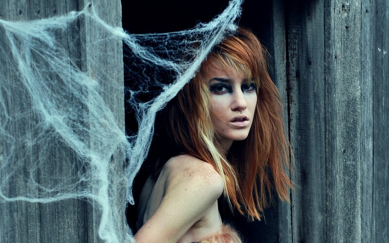 woman with red hair behind cobwebs