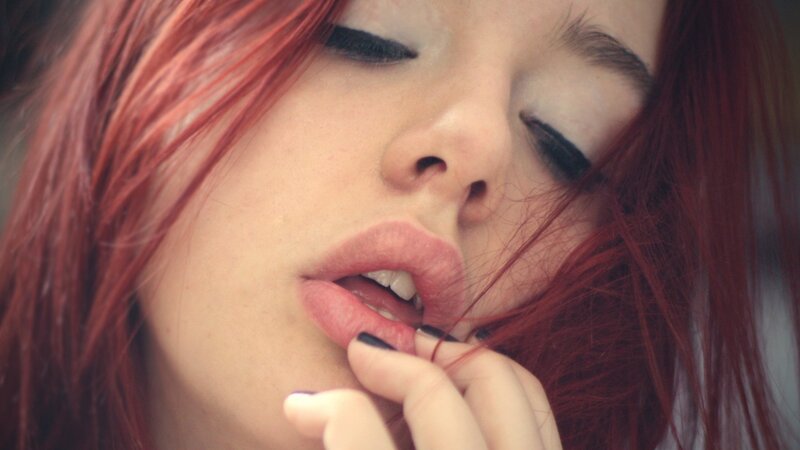 woman with red hair biting lip