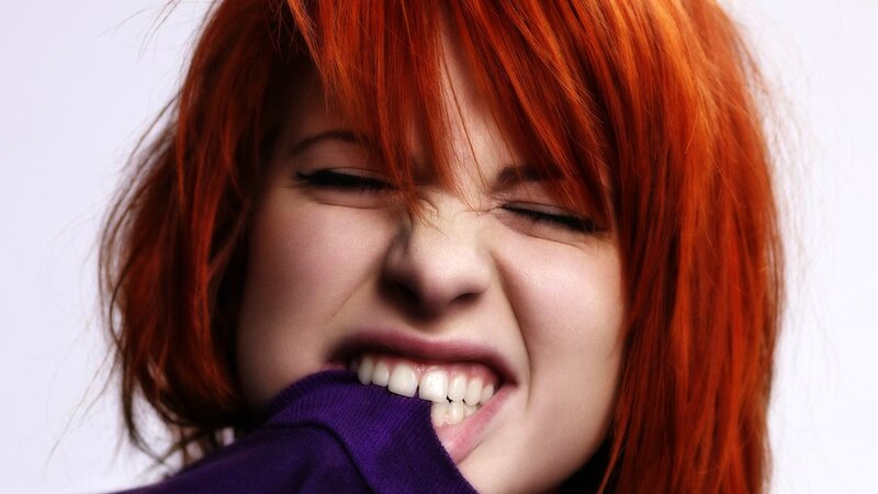 woman with red hair biting sweater