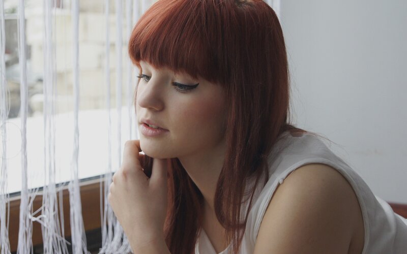 woman with red hair by window