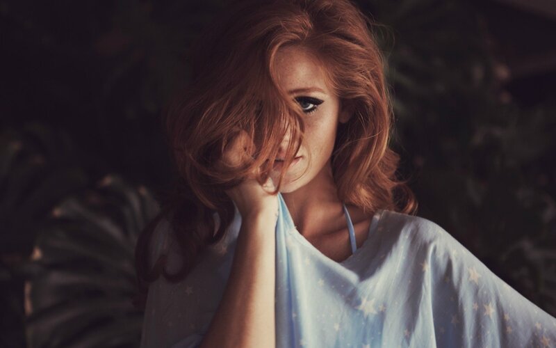 woman with red hair covering face