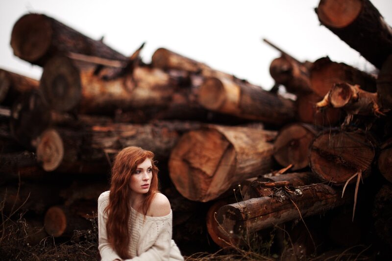 Woman with red hair in a woodpile