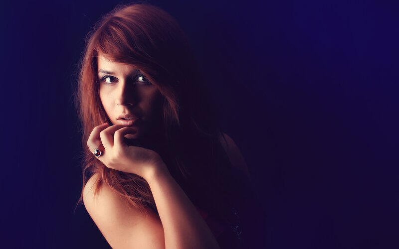 woman with red hair in dark studio