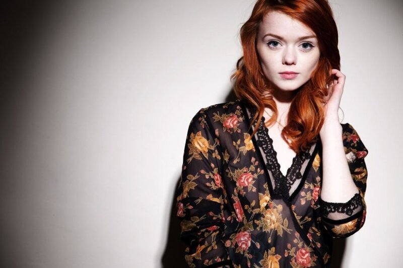 woman with red hair in floral blouse