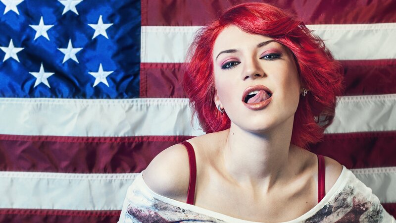 woman with red hair in front of flag