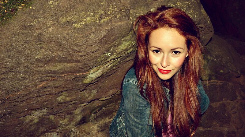 woman with red hair in front of rock