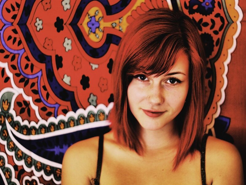 woman with red hair in front of tapestry