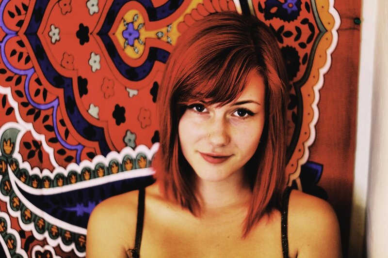 woman with red hair in front of tapestry