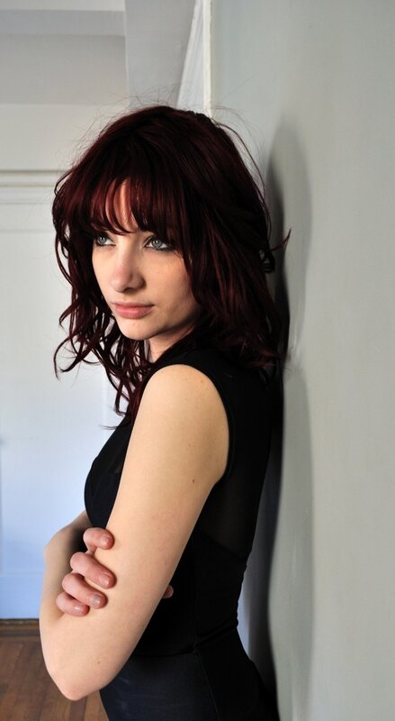 woman with red hair leaning against wall