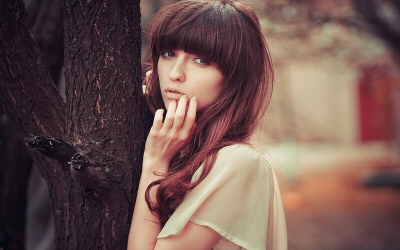 woman with red hair leaning on tree