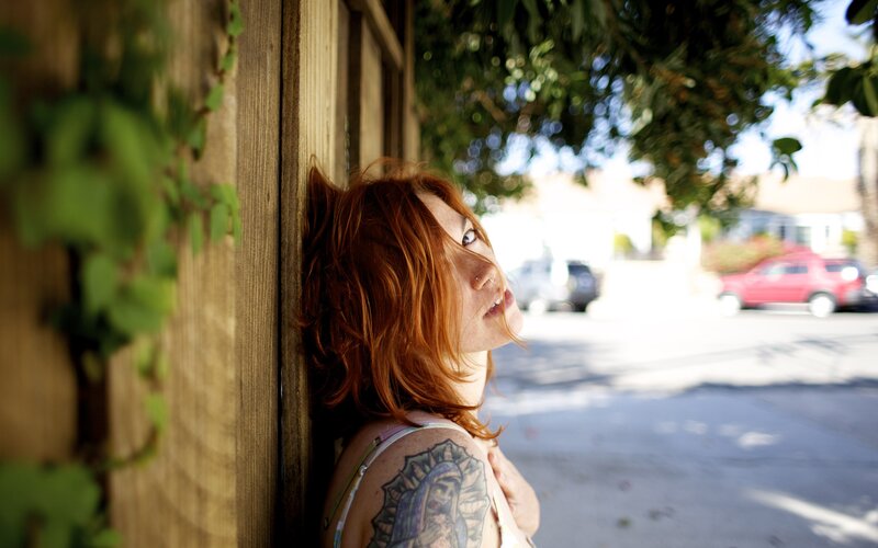 woman with red hair leaning on wall