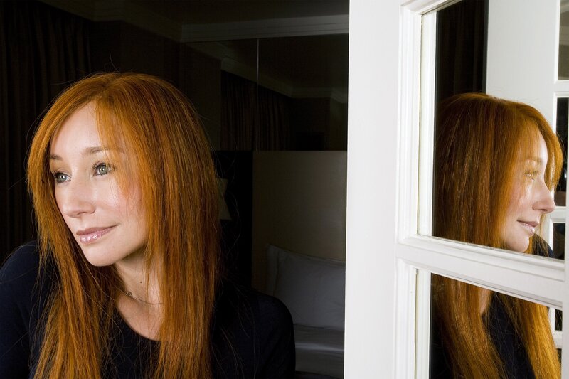 woman with red hair looking out window