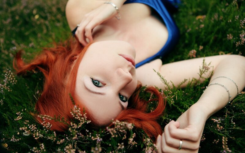 Woman with red hair lying in grass
