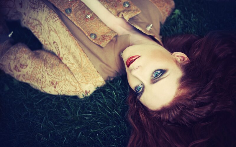 woman with red hair lying on grass