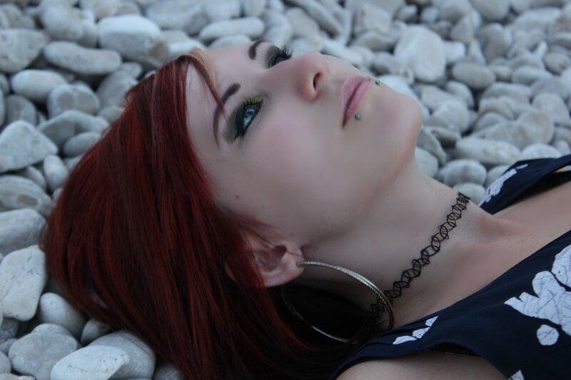 woman with red hair on pebbles