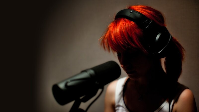 woman with red hair singing into microphone