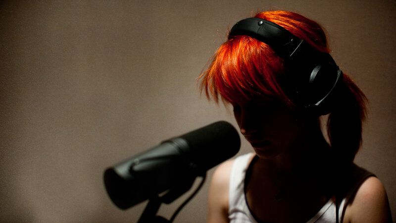 woman with red hair singing into microphone