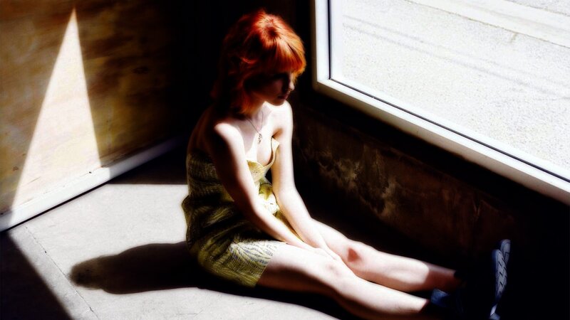 woman with red hair sitting by window