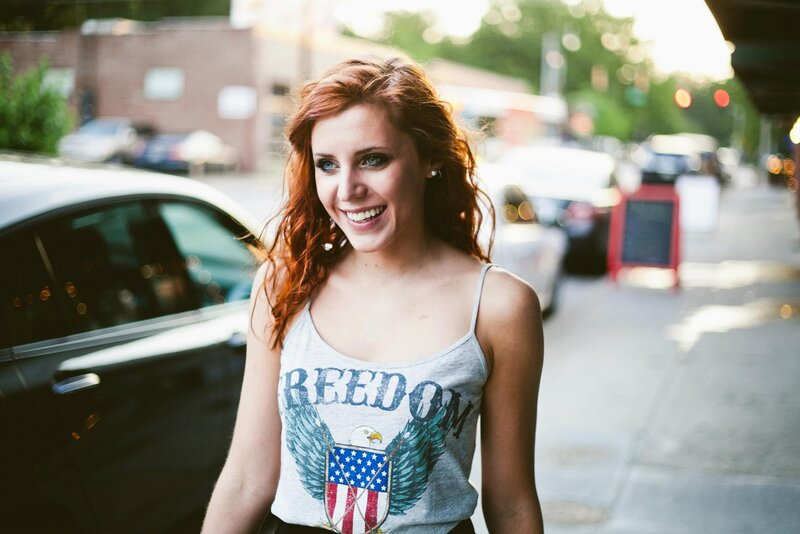 Woman with red hair smiling on street
