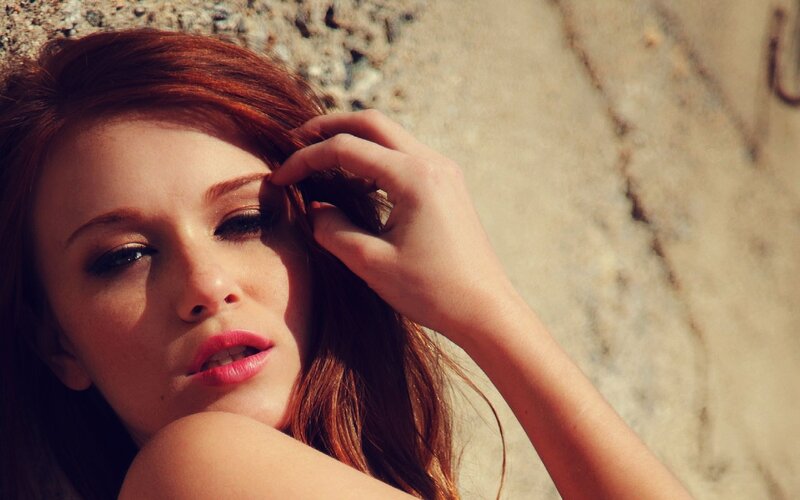woman with red hair touching her face