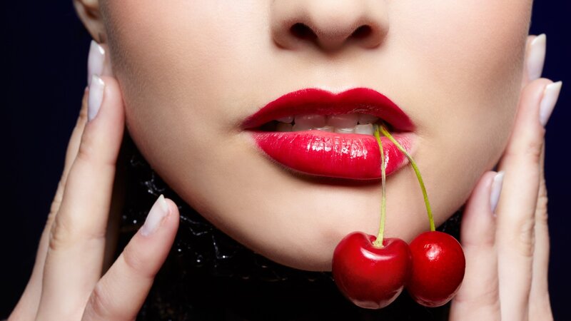 woman with red lips holding cherries