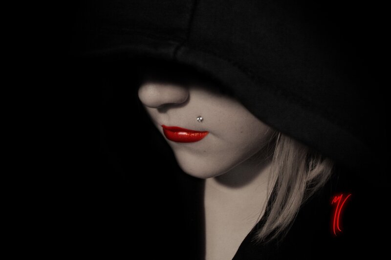 woman with red lips in dark hood