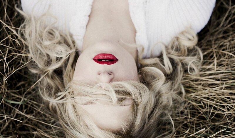 woman with red lips lying in hay