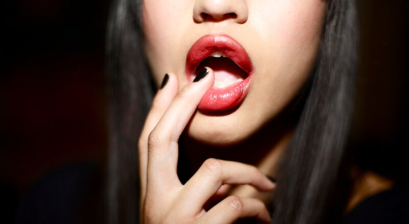 woman with red lipstick and black nails
