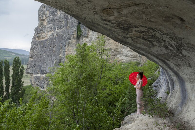 Woman with red parasol in cave