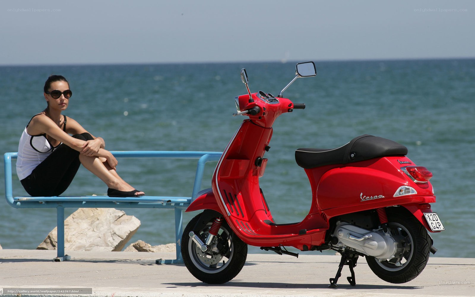 Woman with red scooter by the sea