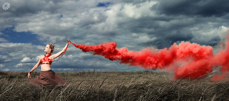 Woman with red smoke in field
