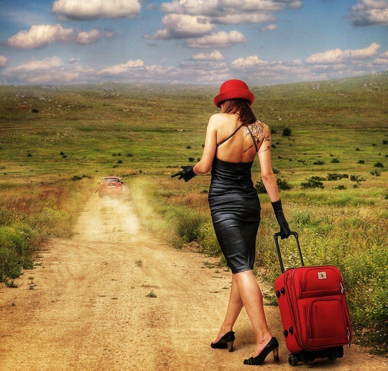 Woman with red suitcase on dirt road