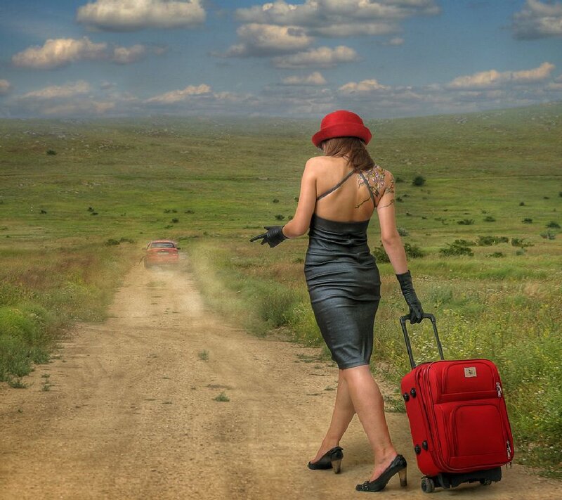 Woman with red suitcase on road