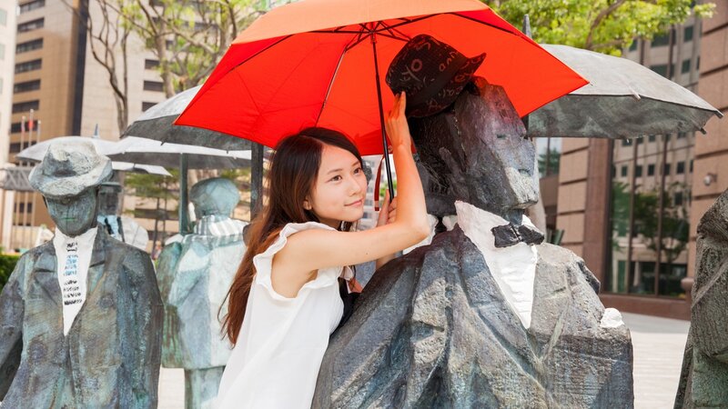 Woman with red umbrella at statue