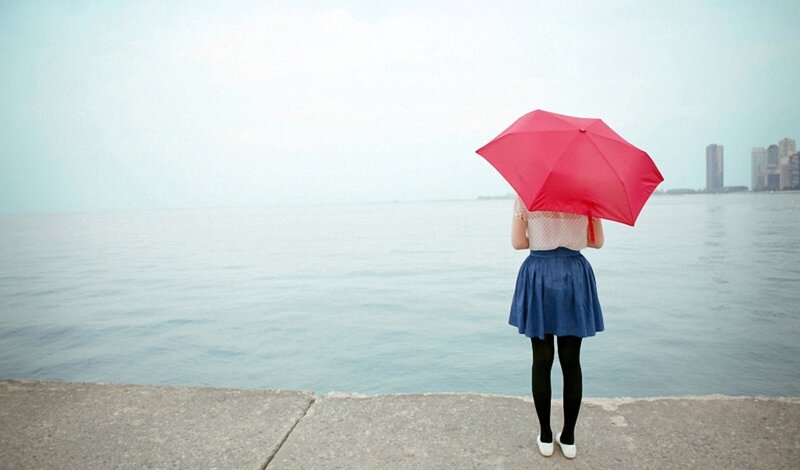 Woman with red umbrella by water