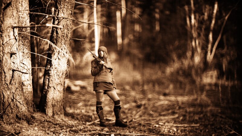 Woman with rifle in forest