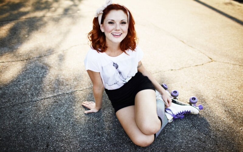 woman with roller skates sitting on pavement