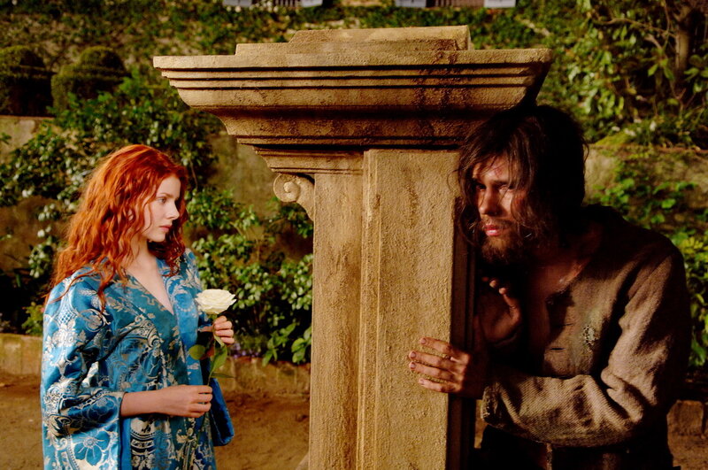 Woman with rose meets man behind pillar